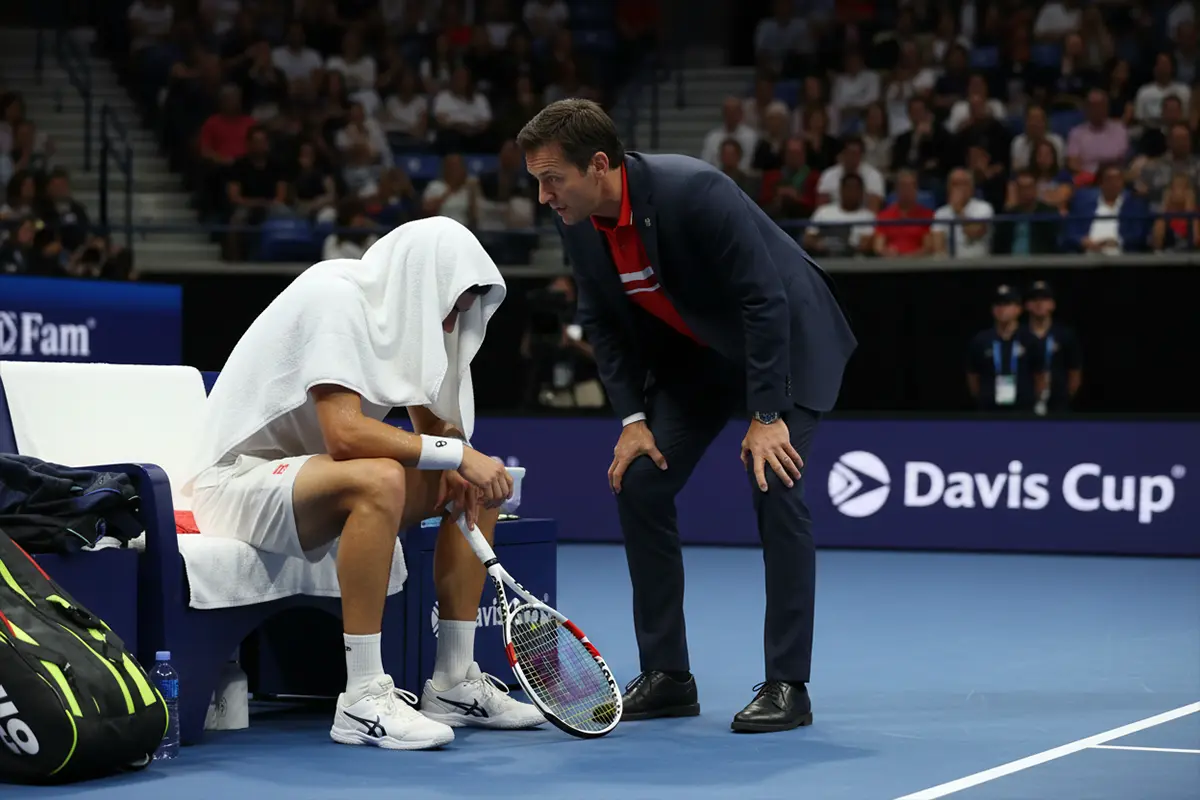 Capitán de tenis hablando con su jugador en el cambio de lado durante un partido de Copa Davis